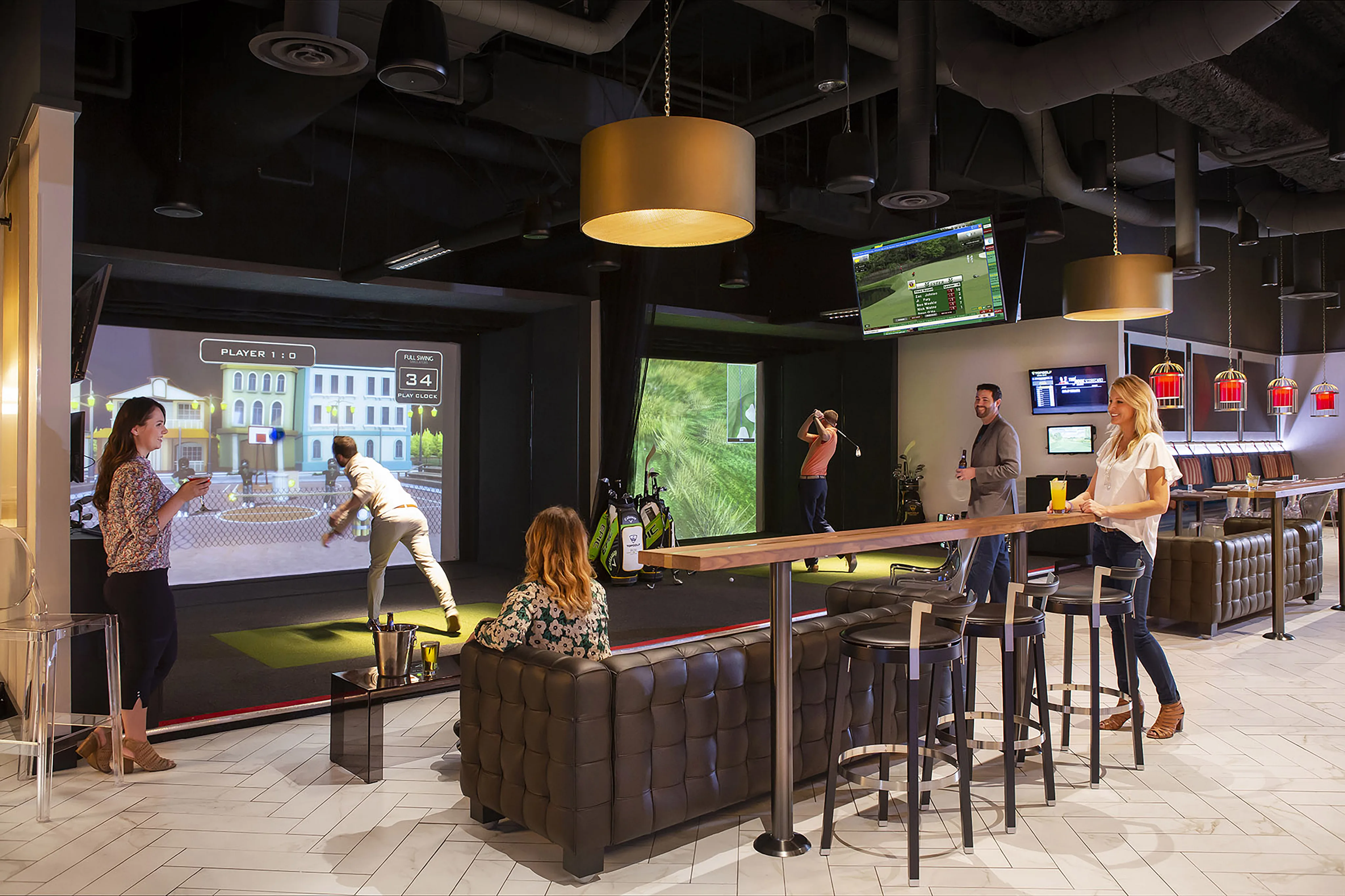 People play virtual golf in the Tempo Top Golf Suite, an indoor entertainment venue with seating, screens, and a bar area; others watch and interact nearby.
